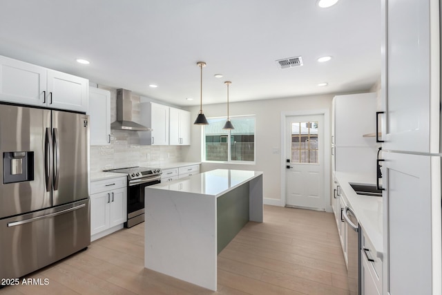 17040 N 39th Ave, Glendale, AZ 85308 - kitchen with stainless steel appliances, wall chimney exhaust hood, a kitchen island, light countertops, and tasteful backsplash