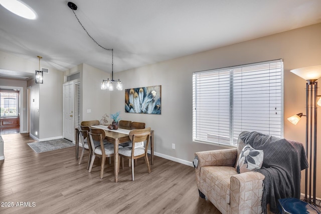 dining area with visible vents, baseboards, an inviting chandelier, lofted ceiling, and wood finished floors