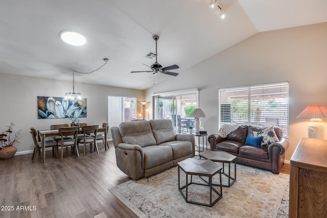 living area featuring light wood-type flooring, visible vents, and ceiling fan with notable chandelier