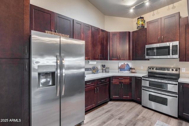 kitchen featuring reddish brown cabinets, appliances with stainless steel finishes, light wood-style floors, and light countertops