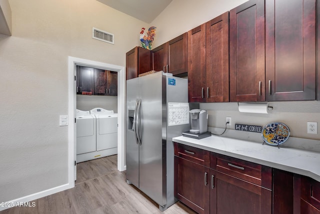 kitchen with light wood-style flooring, visible vents, independent washer and dryer, reddish brown cabinets, and stainless steel fridge with ice dispenser