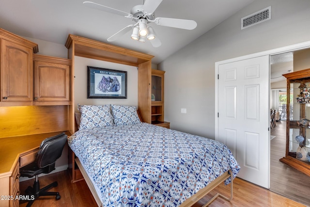 bedroom with wood finished floors, vaulted ceiling, visible vents, and a ceiling fan