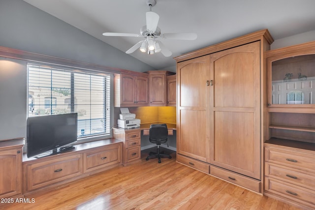 home office featuring light wood-style floors, vaulted ceiling, built in study area, and a ceiling fan