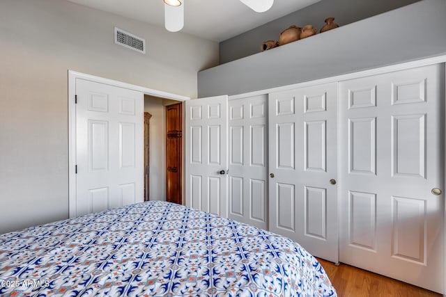 bedroom with light wood finished floors, visible vents, and a closet