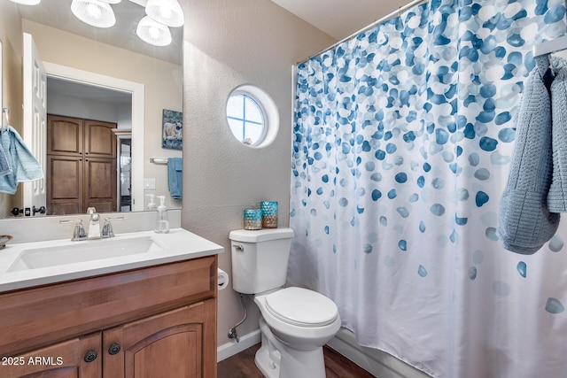 full bathroom with toilet, wood finished floors, a shower with shower curtain, a textured wall, and vanity