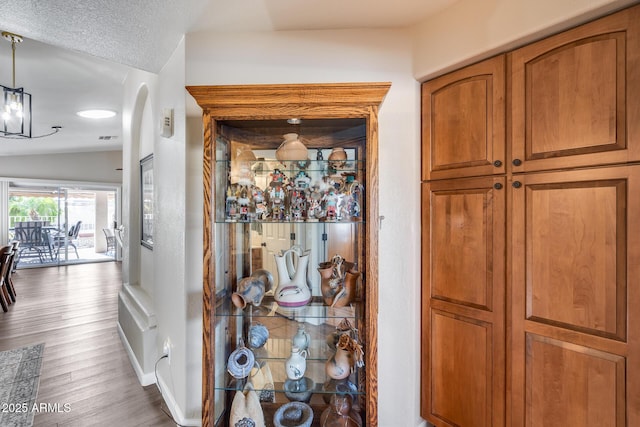 room details with wood finished floors, visible vents, arched walkways, baseboards, and a chandelier