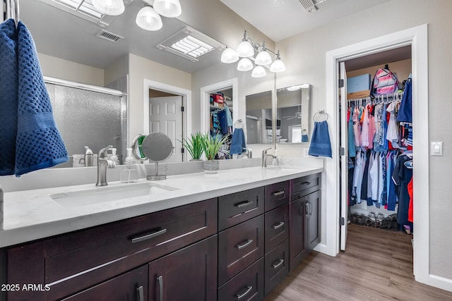 full bath featuring a spacious closet, visible vents, a sink, and double vanity