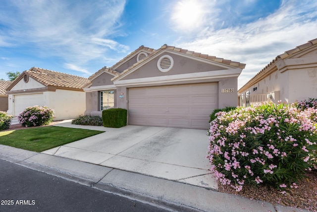 view of front of house with stucco siding, a tiled roof, driveway, and a garage