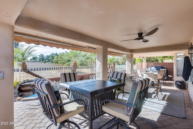 view of patio with outdoor dining area, fence, and ceiling fan