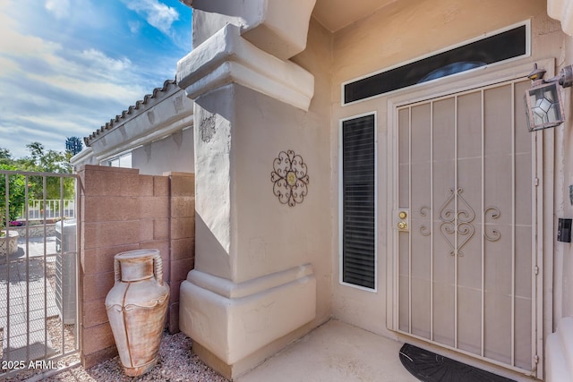 property entrance with stucco siding and fence