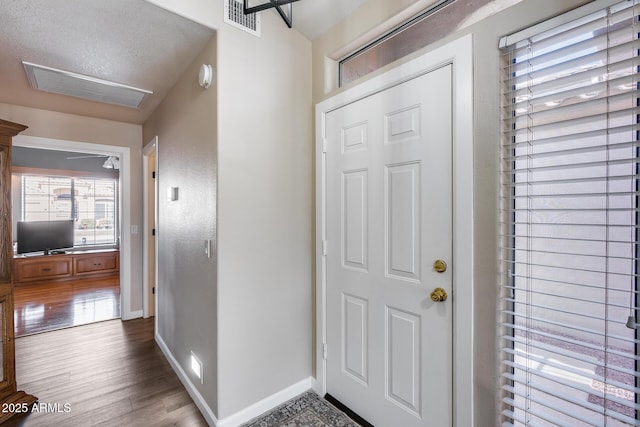 foyer entrance with wood finished floors, visible vents, and baseboards