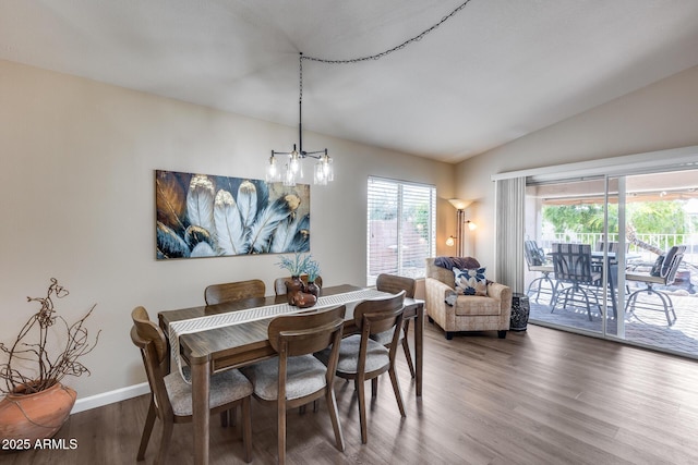 dining area featuring a chandelier, lofted ceiling, baseboards, and wood finished floors