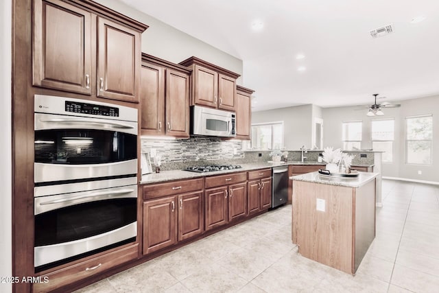 5541 W Desperado Way, Phoenix, AZ 85083 - kitchen with stainless steel appliances, ceiling fan, tasteful backsplash, light tile patterned floors, and a center island