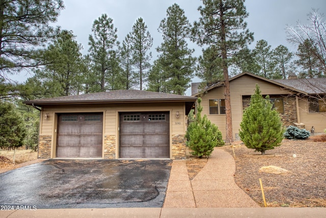 view of front of property with an outbuilding, stone siding, and a detached garage