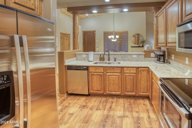 kitchen with stainless steel appliances, a peninsula, a sink, light wood-type flooring, and light stone countertops