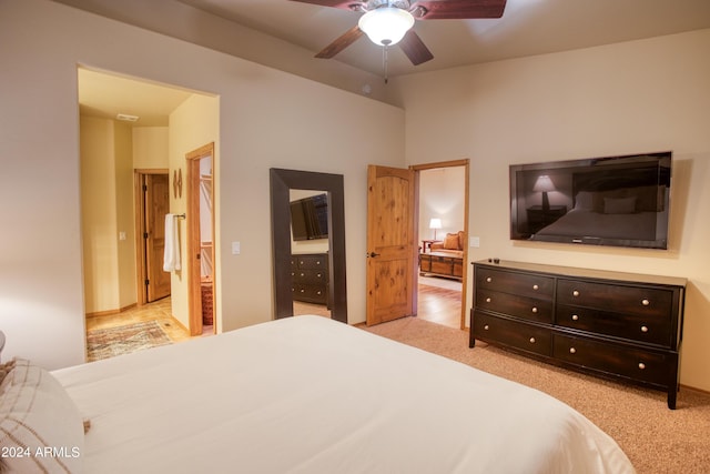 bedroom with light carpet, a ceiling fan, and connected bathroom