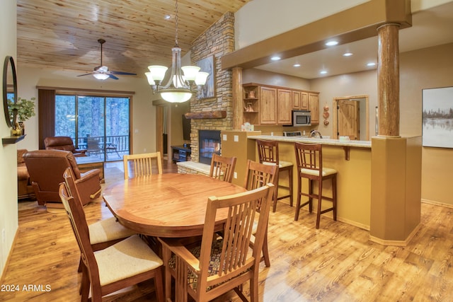 dining area with a fireplace, decorative columns, light wood finished floors, ceiling fan, and wooden ceiling