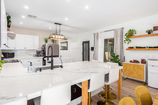 kitchen featuring visible vents, black microwave, a breakfast bar, a peninsula, and a sink