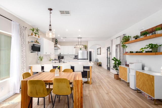 dining room with visible vents, arched walkways, baseboards, and light wood-style flooring