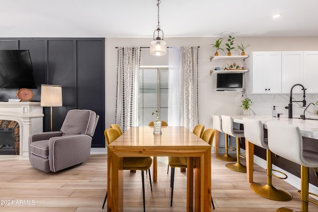 dining area featuring recessed lighting, light wood-style flooring, and a fireplace