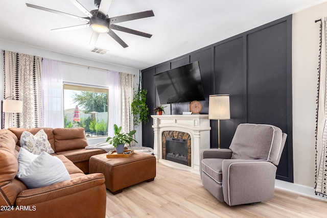 living room featuring visible vents, a fireplace, a ceiling fan, and light wood-style floors