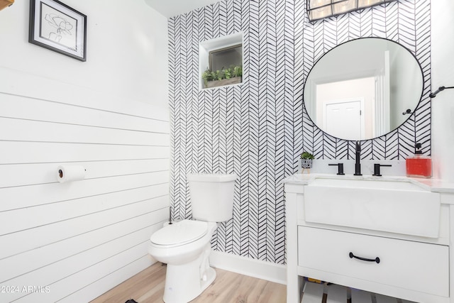 half bath featuring toilet, wood finished floors, and vanity