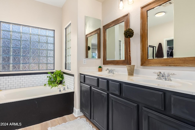 full bath with double vanity, visible vents, a garden tub, and a sink