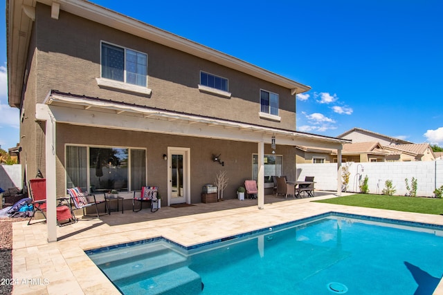 back of property with stucco siding, fence, a fenced in pool, and a patio area