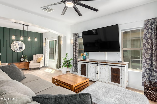 living area with a ceiling fan, wood finished floors, and visible vents