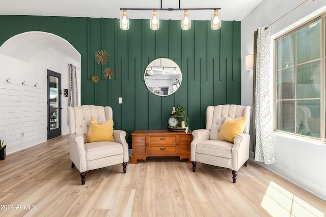 living area featuring a wealth of natural light, arched walkways, and light wood-style floors