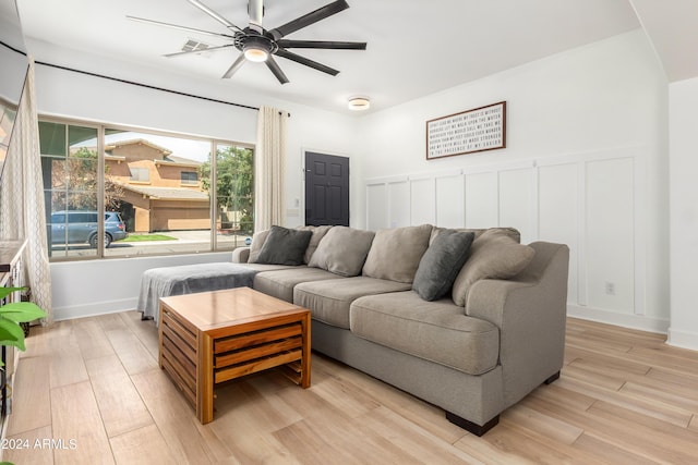 living room with a decorative wall, ceiling fan, and light wood finished floors