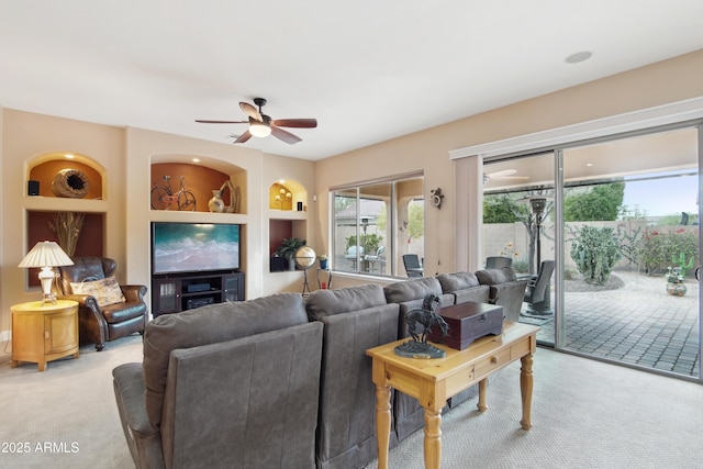 living room featuring ceiling fan, built in shelves, and light carpet