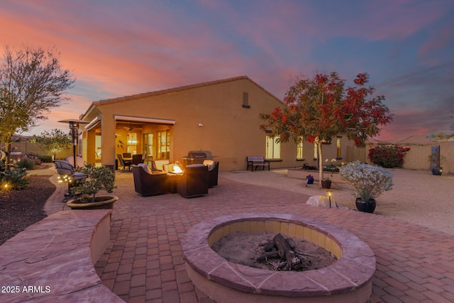 patio terrace at dusk with an outdoor living space with a fire pit