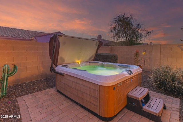 patio terrace at dusk featuring a hot tub