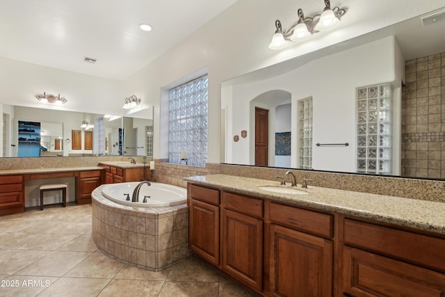 bathroom with tiled bath, tile patterned floors, and vanity