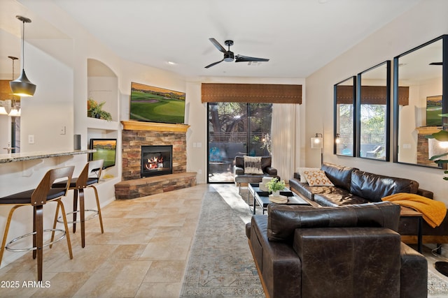 living room featuring ceiling fan and a stone fireplace