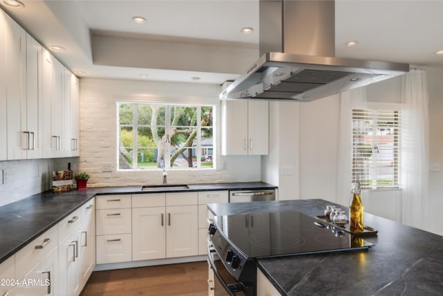 kitchen with island exhaust hood, decorative backsplash, white cabinets, and a wealth of natural light