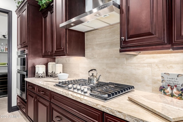 kitchen with appliances with stainless steel finishes, backsplash, light stone counters, and wall chimney exhaust hood