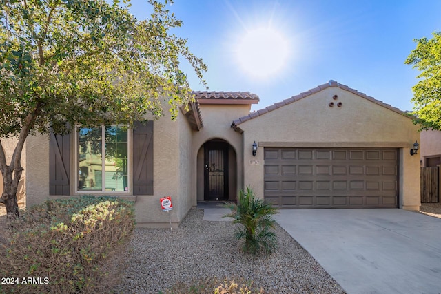 mediterranean / spanish-style house with driveway, a tiled roof, a garage, and stucco siding