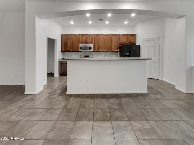 kitchen featuring tasteful backsplash, recessed lighting, black fridge, stainless steel microwave, and baseboards