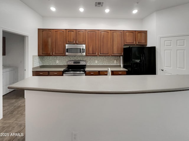 kitchen featuring light countertops, visible vents, stainless steel appliances, tasteful backsplash, and washer / dryer