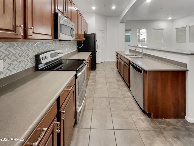 kitchen with tasteful backsplash, a sink, arched walkways, light tile patterned flooring, and appliances with stainless steel finishes