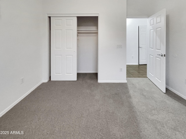 unfurnished bedroom with carpet flooring, baseboards, and a closet