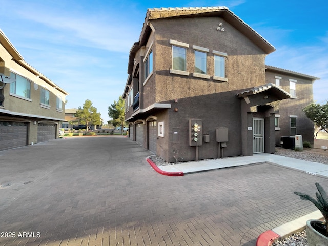 exterior space with stucco siding, an attached garage, a tiled roof, and driveway