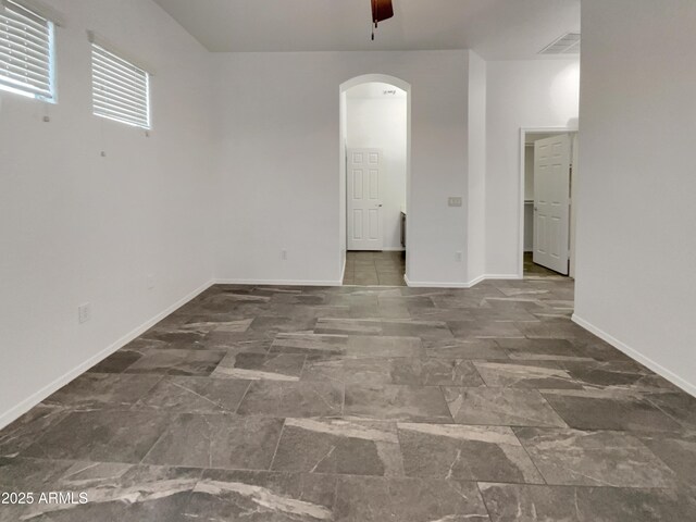 unfurnished room with baseboards, visible vents, and arched walkways