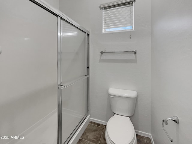 full bath with baseboards, toilet, tile patterned flooring, and a shower stall