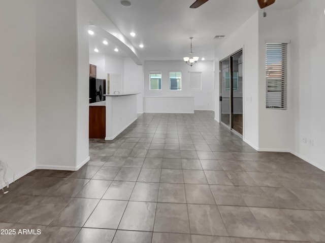 interior space featuring tile patterned flooring, recessed lighting, ceiling fan with notable chandelier, baseboards, and visible vents