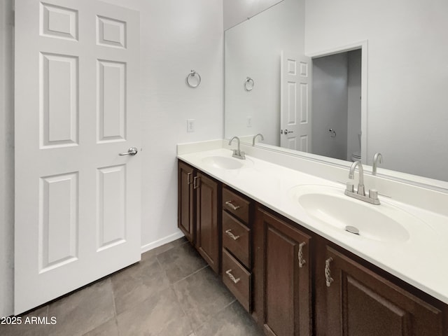 bathroom featuring baseboards, double vanity, a sink, and toilet