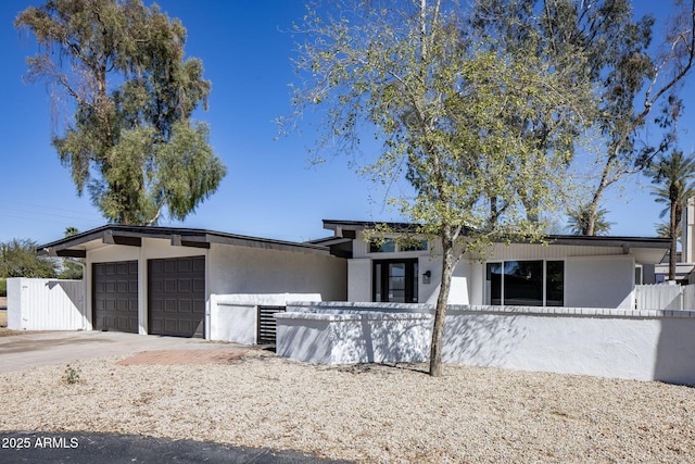 view of front of home with a fenced front yard, stucco siding, an attached garage, and concrete driveway