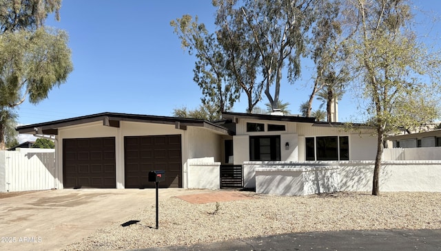 view of front of property featuring a fenced front yard, driveway, and a garage